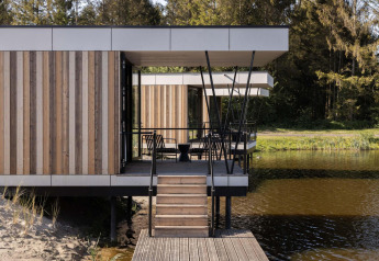 Alojamiento de glamping moderno sobre el agua, con terraza, paneles de madera y vistas a la naturaleza.