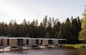 Cabañas de glamping modernas sobre pilotes junto a un lago, rodeadas de bosque, ideal para relajarse.