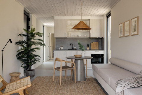 Moderne glampingaccommodatie met keuken, comfortabele zitruimte, eettafel en natuurlijke decoratie.