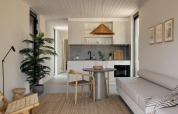Modern glamping accommodation interior with kitchen, cozy lounge area, dining table and natural decor.