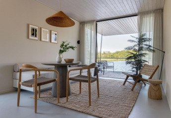 Alojamiento glamping moderno con decoración minimalista, vista al lago y acceso a una terraza exterior.