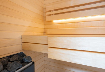 Vista interior de una sauna moderna con paneles de madera y piedras en Waterlodge Sauna, Resort de Parel, Países Bajos.