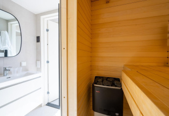 Modern badkamerontwerp met aangrenzende houten sauna en kachel bij Waterlodge Sauna, Resort de Parel.