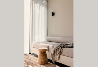 Helles Glamping-Apartment mit gemütlichem Sofa, Holztisch, Teppich und lichtdurchfluteten Vorhängen.