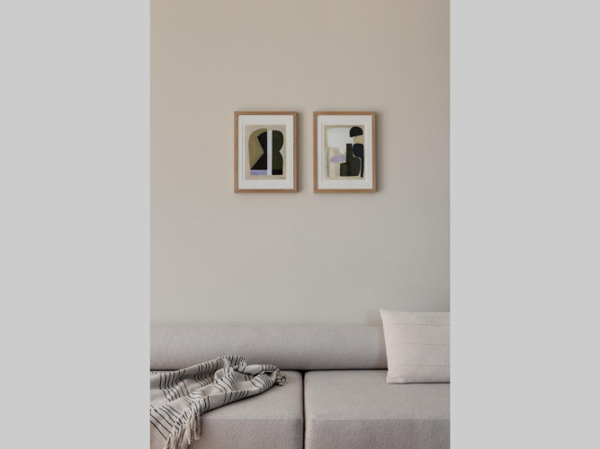 Moderne zithoek met beige bank, abstracte wandkunst en gezellige deken in een glamping-accommodatie.