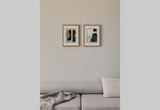 Moderne leefhoek met beige zetel, abstracte muurkunst en zachte plaid in een glampingverblijf.