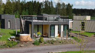Moderne lodge met dakterras en hottub bij Resort de Parel in Nederland, omgeven door groen en bomen.