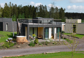 Moderne lodge met dakterras en hottub bij Resort de Parel in Nederland, omgeven door groen en bomen.