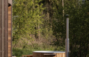 Houtgestookte hottub en lodge tussen bomen bij Resort de Parel in Nederland, midden in het groen.