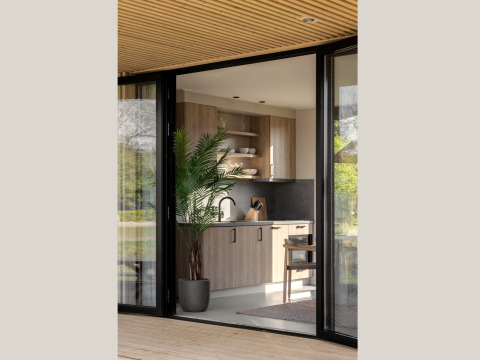Cuisine de lodge moderne avec meubles en bois, plante verte en pot, étagères ouvertes et portes vitrées.