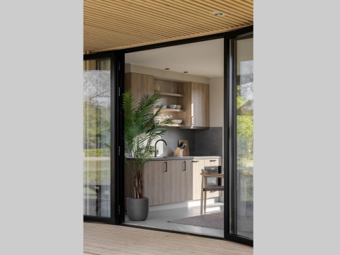 Cuisine de lodge moderne avec meubles en bois, plante verte en pot, étagères ouvertes et portes vitrées.