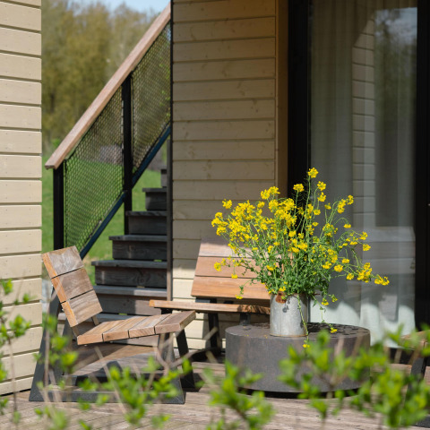 Zonnig terras bij Villa Roof Terrace + Hot tub, Resort de Parel, met houten stoelen en bloemen in een kan.