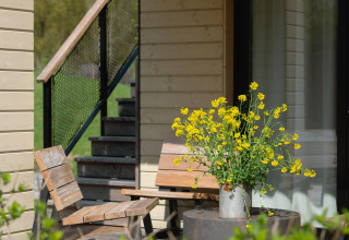 Zonnig terras aan Villa Roof Terrace + Hot tub, Resort de Parel, met houten stoelen en bloemen in een kan.