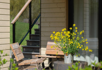 Zonnig terras aan Villa Roof Terrace + Hot tub, Resort de Parel, met houten stoelen en bloemen in een kan.