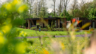 Lodge Jacuzzi im Resort de Parel in den Niederlanden, eingebettet im Grünen, mit Bäumen und einer Person im Garten.