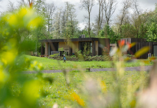 Lodge Jacuzzi im Resort de Parel in den Niederlanden, eingebettet im Grünen, mit Bäumen und einer Person im Garten.