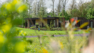 Foto van Lodge Jacuzzi bij Resort de Parel in Nederland, omgeven door groen, met een persoon op het gras.
