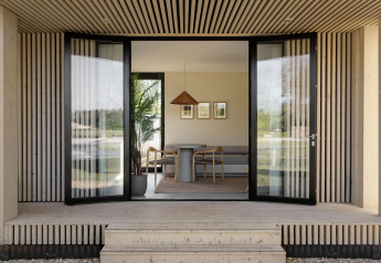 Ingresso aperto a un lodge moderno con pannelli in legno, ampie porte a vetri e arredamento minimalista.