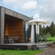 Villa moderna de madera con tumbonas, sombrilla y mesa de picnic en Resort de Parel, rodeada de naturaleza.