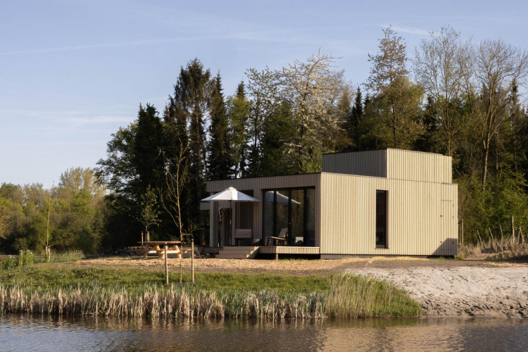Villa moderna junto al lago en Resort de Parel, Países Bajos, rodeada de árboles y naturaleza.
