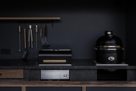 Modern outdoor kitchen at Lodge Culinary, Resort de Parel, Netherlands, with grill and kitchen tools.