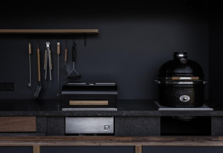 Modern outdoor kitchen at Lodge Culinary, Resort de Parel, Netherlands, with grill and kitchen tools.