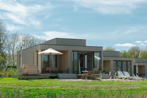 Moderne Villa Hottub lodge op Resort de Parel in Nederland, met terras, ligstoelen en groene tuin.