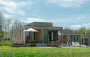 Moderne Villa Hottub-lodge ved Resort de Parel i Holland, med træfacade, terrasse og solsenge.
