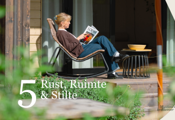 Mujer relajándose con una revista en la terraza de Villa Hottub en Resort de Parel, Países Bajos, rodeada de naturaleza.