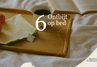 Desayuno en la cama con té, mandarinas y un libro abierto en Villa Hottub, Resort de Parel, Países Bajos.