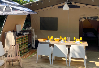 Safari Base Lodge ved Camping Gajole i Italien med åbent telt, spisebord, køkken og udendørs parasol.