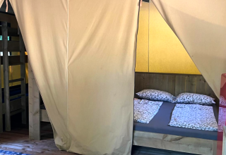 Indvendigt billede af Base Lodge safari telt på Camping Gajole i Italien med seng og køjesenge.