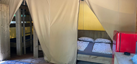 Vista interna di una tenda safari Base Lodge al Camping Gajole in Italia con letto matrimoniale e a castello.
