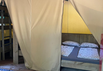 Vista interna di una tenda safari Base Lodge al Camping Gajole in Italia con letto matrimoniale e a castello.