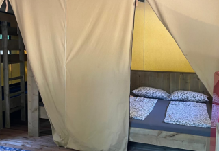 Interior view of Base Lodge safari tent at Camping Gajole in Italy featuring a double bed and bunk beds.