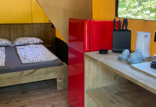 Base Lodge safaritent bij Camping Gajole in Italië met tweepersoonsbed, keukenblok en rode koelkast.
