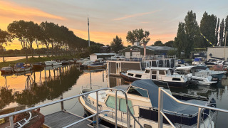 Woonboot bij Havenlodge+ Amsterdam in Marina Parcs, met boten en zonsondergang in Amsterdam, Nederland.
