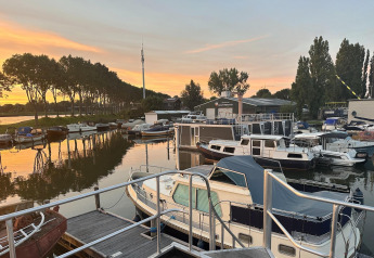Woonboot bij Havenlodge+ Amsterdam in Marina Parcs, met boten en zonsondergang in Amsterdam, Nederland.