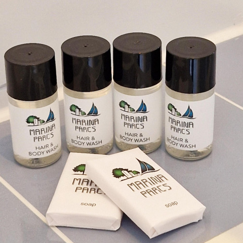 Toiletries on a houseboat bathroom: four Marina Parcs Hair & Body Wash bottles and two soap packages.