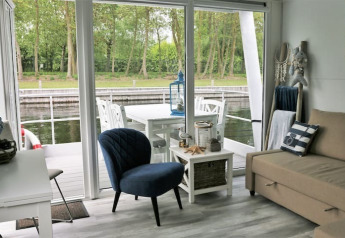 Cozy living area on a Havenlodge+ Amsterdam houseboat with water view at Marina Parcs Amsterdam, Netherlands.