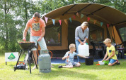Familia acampando en una tienda safari en CharmeCamping De Regge-Vallei, Países Bajos, cocina y juegos.