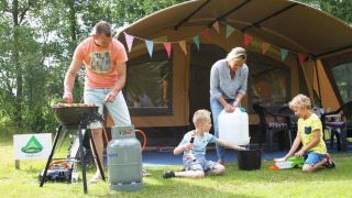 Famille en camping dans une tente safari à CharmeCamping De Regge-Vallei, Pays-Bas, cuisine et jeux dehors.