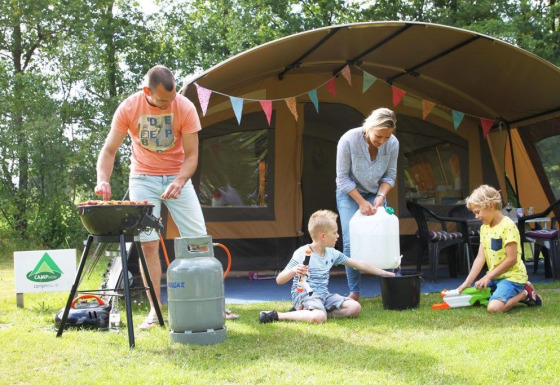 Familia acampando en una tienda safari en CharmeCamping De Regge-Vallei, Países Bajos, cocina y juegos.