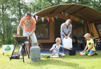 Famille en camping dans une tente safari à CharmeCamping De Regge-Vallei, Pays-Bas, cuisine et jeux dehors.