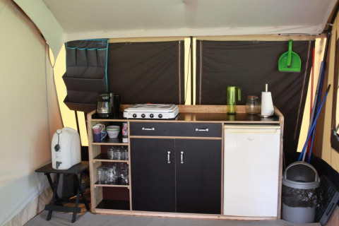 Cocina interior en tienda safari en CharmeCamping De Regge-Vallei, Países Bajos, con utensilios y electrodomésticos.