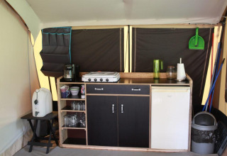 Angolo cucina all’interno di una tenda safari a CharmeCamping De Regge-Vallei, Paesi Bassi, con attrezzature.