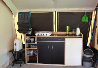 Angolo cucina all’interno di una tenda safari a CharmeCamping De Regge-Vallei, Paesi Bassi, con attrezzature.