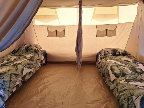 Intérieur d'une tente safari au CharmeCamping De Regge-Vallei aux Pays-Bas avec deux lits simples.