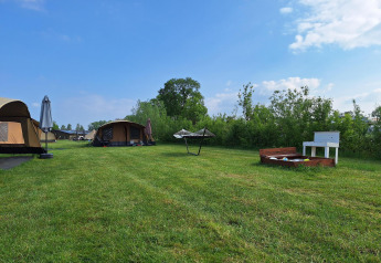 Tenda safari al CharmeCamping De Regge-Vallei nei Paesi Bassi con prato, amaca e area giochi per bambini.