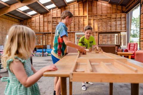 Kinderen spelen een gezelschapsspel in een grote safaritent op CharmeCamping De Regge-Vallei in Nederland.
